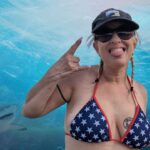 Queen Daisy Chain holding a fishing pole in an American themed bikini