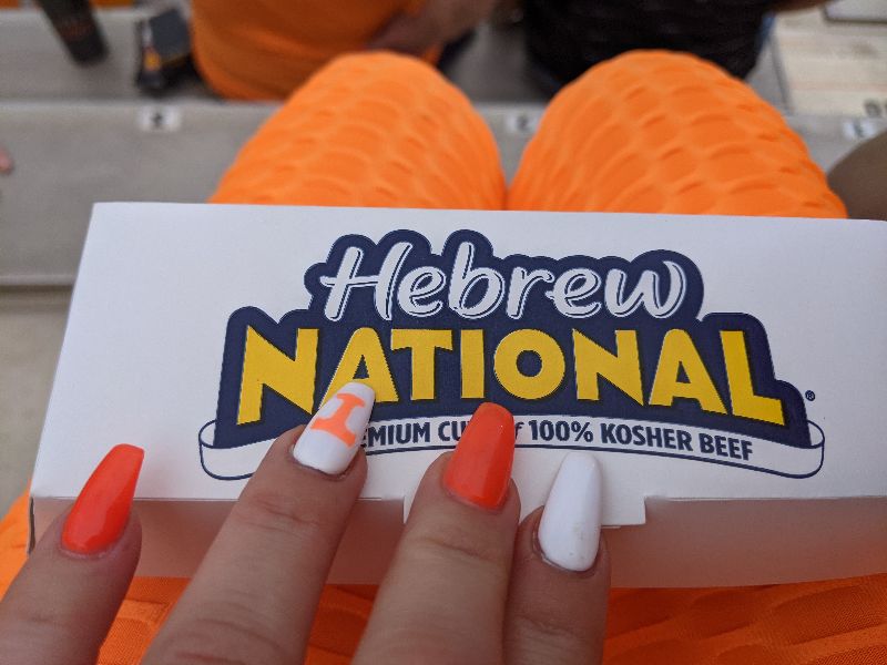 Daisy Chain has Vols painted nails, organge leggings, and is holding a Hebrew National Hot Dog at Vols Stadium in Knoxville, TN