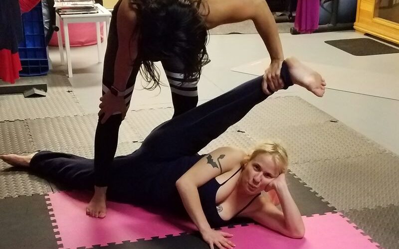 Queen Daisy Chain, the 4'11" pocket pretzel is doing a leg stretch with the assistance of her trainer.