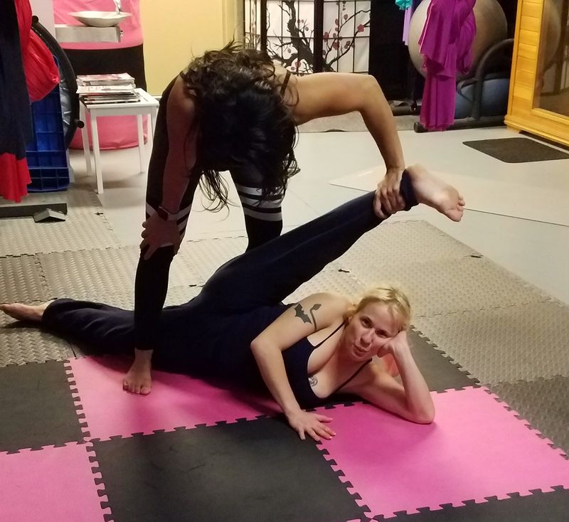 Queen Daisy Chain, the 4'11" pocket pretzel is doing a leg stretch with the assistance of her trainer.